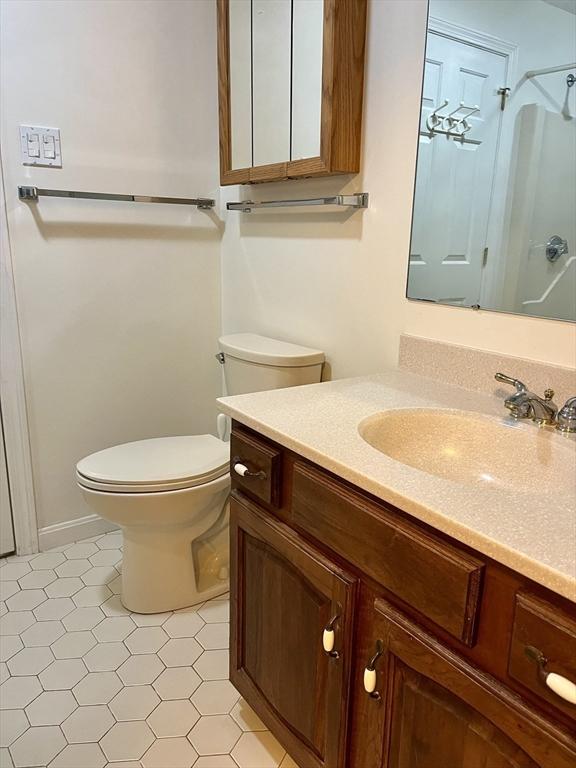 bathroom featuring toilet, a shower, and vanity