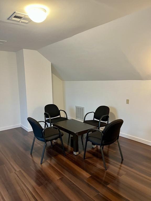 sitting room featuring baseboards, vaulted ceiling, visible vents, and dark wood finished floors