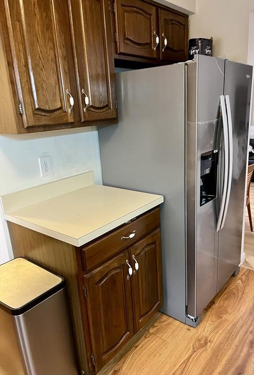 kitchen with light countertops, light wood-style floors, dark brown cabinetry, and stainless steel fridge with ice dispenser