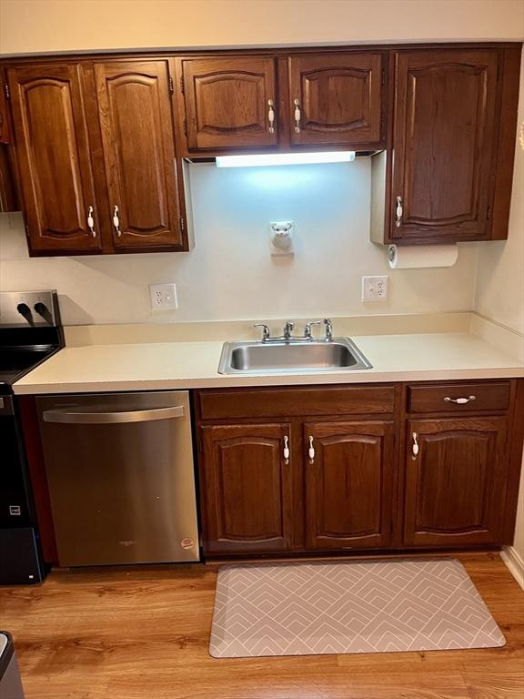 kitchen featuring a sink, electric range oven, light countertops, and dishwasher