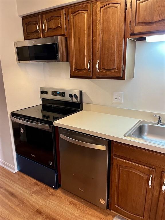 kitchen featuring light countertops, appliances with stainless steel finishes, light wood-type flooring, and a sink