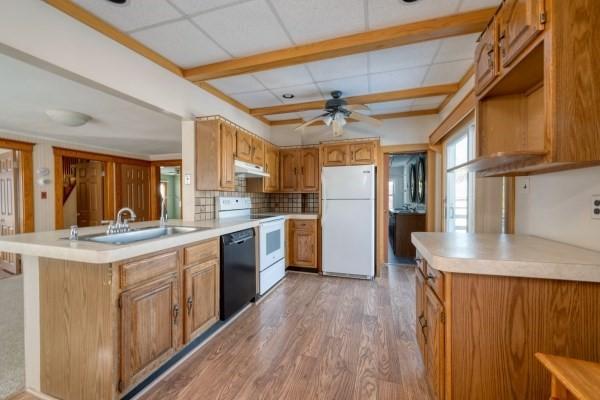 kitchen with light countertops, white appliances, a sink, and brown cabinets