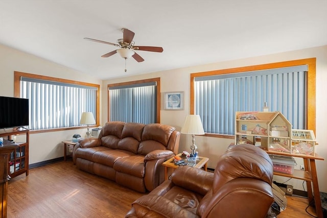 living area with a ceiling fan, lofted ceiling, wood finished floors, and baseboards