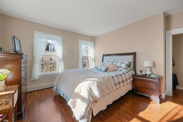 bedroom featuring a baseboard heating unit, wood finished floors, and baseboards