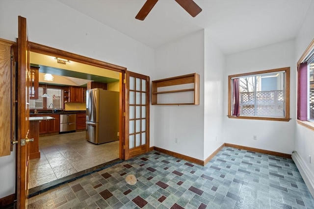 interior space with a ceiling fan, baseboards, and a sink