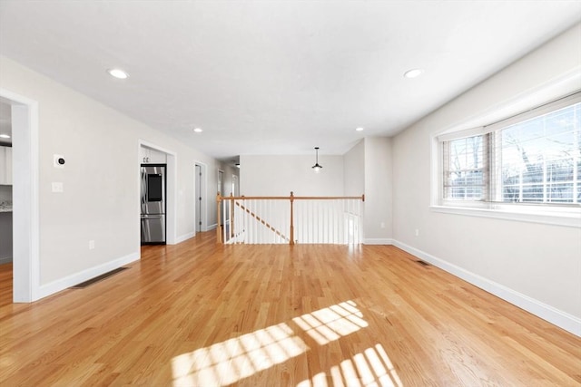 empty room with light wood-type flooring, visible vents, baseboards, and recessed lighting