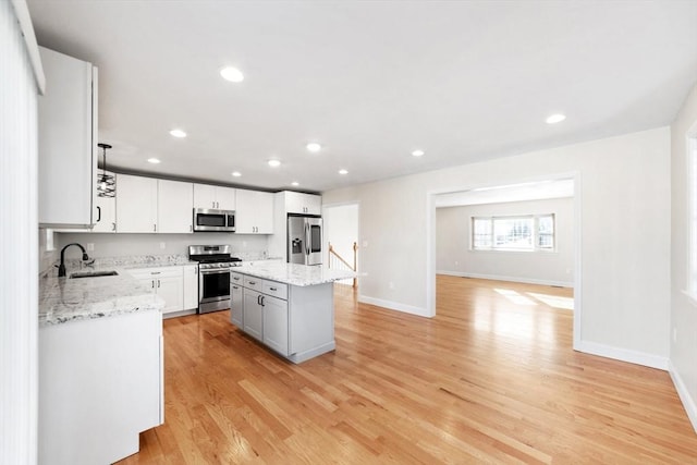 kitchen with light wood-style flooring, a kitchen island, appliances with stainless steel finishes, a sink, and recessed lighting