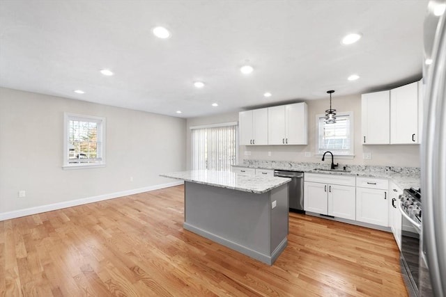 kitchen with appliances with stainless steel finishes, a sink, light wood-style flooring, and a center island