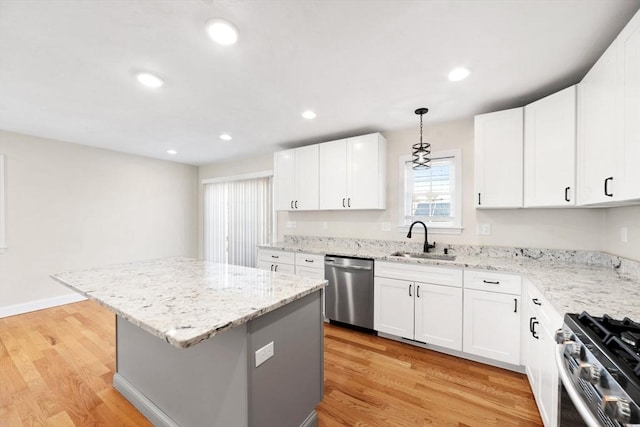 kitchen featuring appliances with stainless steel finishes, a kitchen island, a sink, and light wood-style flooring