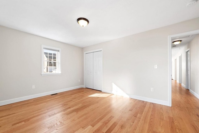 unfurnished bedroom featuring a closet, visible vents, light wood-style flooring, and baseboards