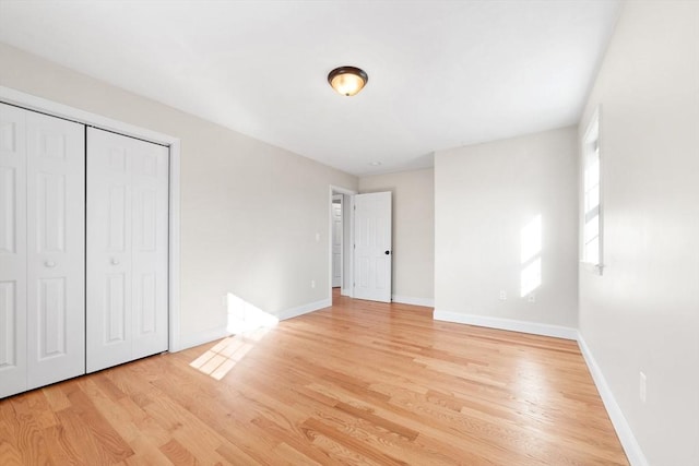 unfurnished bedroom with light wood-type flooring, baseboards, and a closet