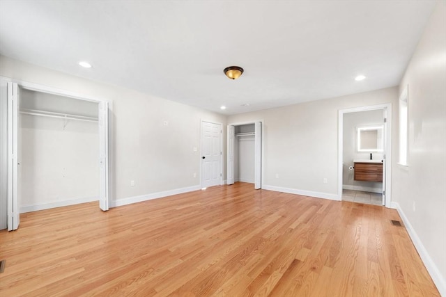 unfurnished bedroom featuring two closets, recessed lighting, visible vents, light wood-type flooring, and baseboards