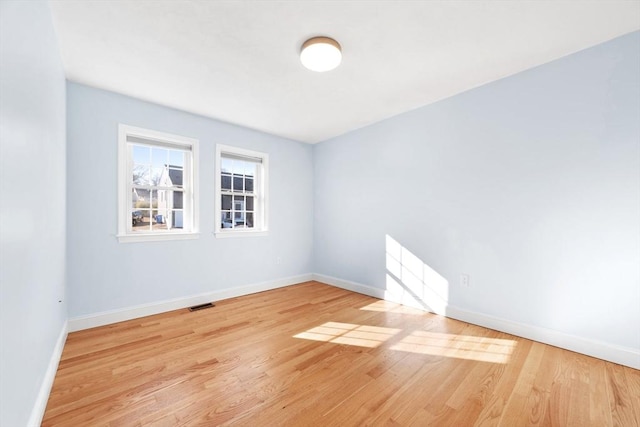 empty room featuring light wood finished floors, visible vents, and baseboards