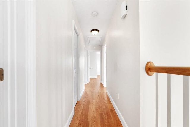 corridor with light wood finished floors, attic access, and baseboards