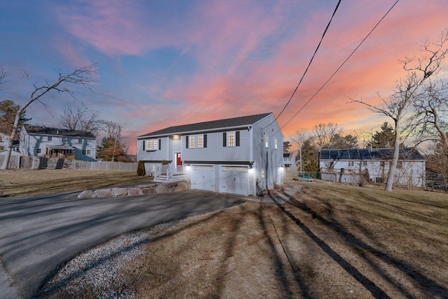 bi-level home featuring a garage, driveway, and fence