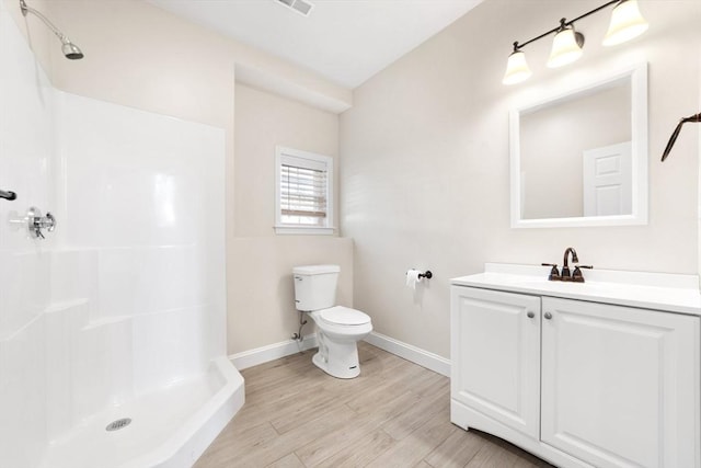 bathroom featuring a shower, vanity, toilet, and wood finished floors