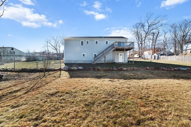 rear view of house featuring a deck, a yard, stairway, and fence