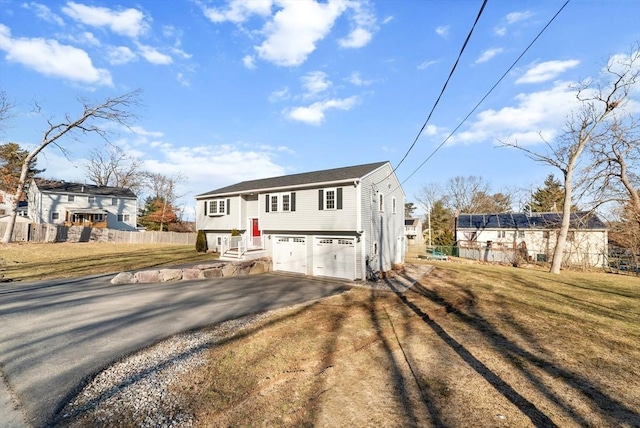 split foyer home featuring driveway, an attached garage, and fence