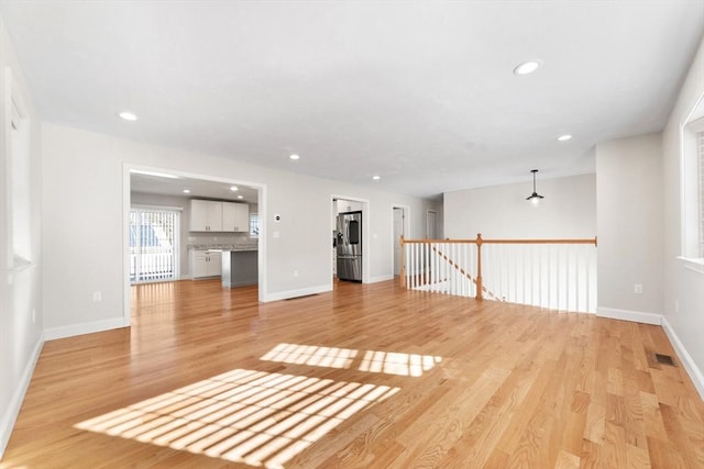 unfurnished living room with baseboards, recessed lighting, and light wood-style floors