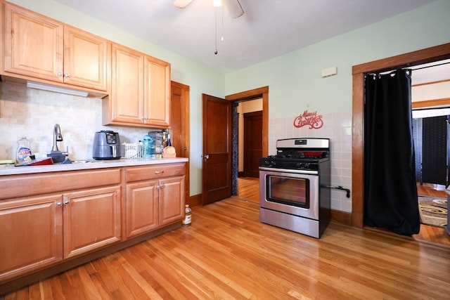 kitchen with ceiling fan, gas stove, sink, and light hardwood / wood-style floors