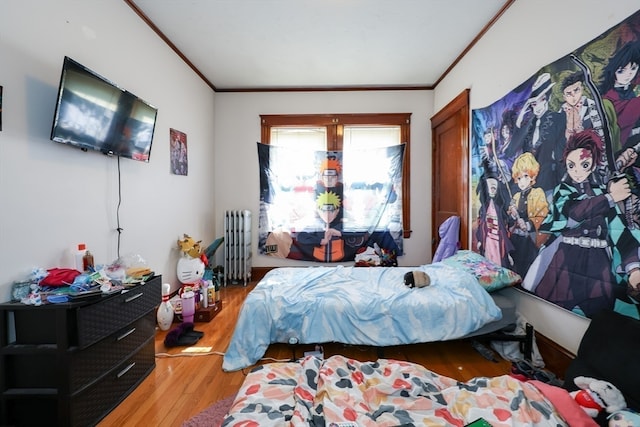 bedroom featuring wood-type flooring, radiator heating unit, and ornamental molding