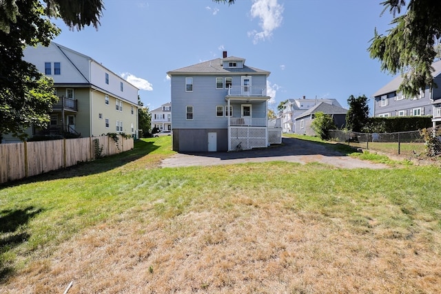 back of property with a yard and a balcony