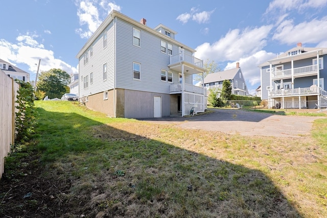 back of property with a balcony and a lawn