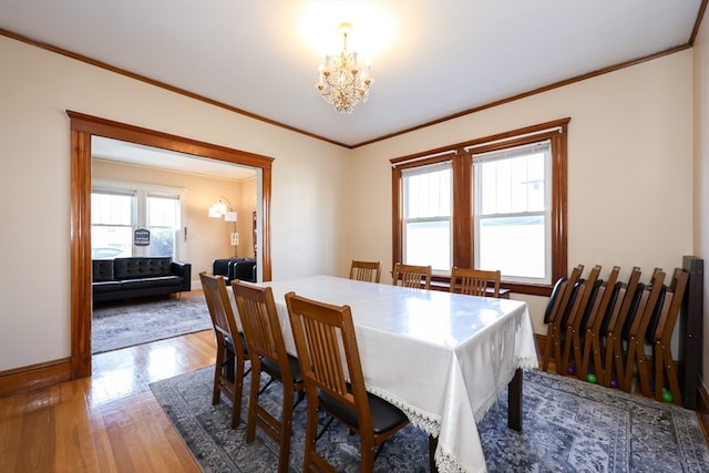 dining area featuring wood-type flooring, crown molding, and a chandelier