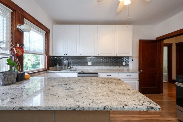 kitchen featuring light stone counters, white cabinets, hardwood / wood-style floors, and tasteful backsplash