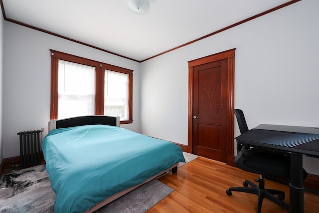 bedroom with ornamental molding, hardwood / wood-style flooring, and radiator heating unit