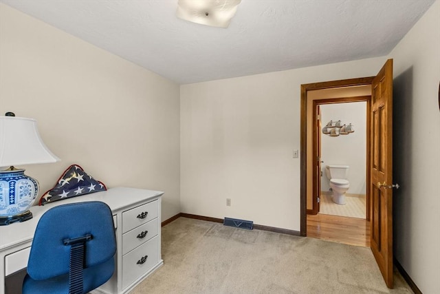 home office with baseboards, visible vents, and light carpet