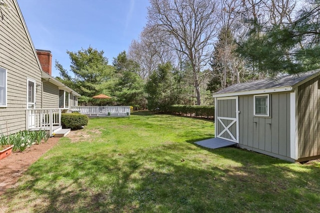 view of yard featuring a storage unit, an outbuilding, and a deck