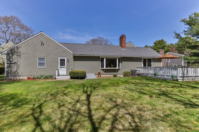 rear view of property with a chimney, a yard, and a deck