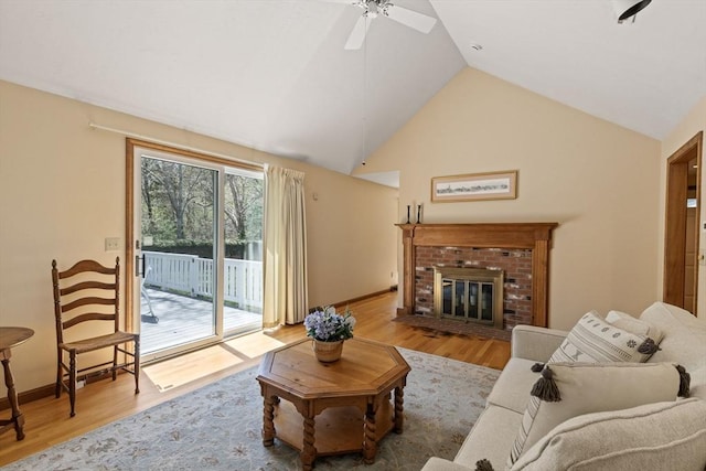 living area with a brick fireplace, a ceiling fan, baseboards, and wood finished floors