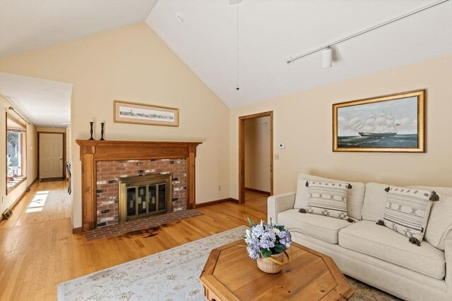 living area featuring light wood-style floors, baseboards, lofted ceiling, and a fireplace