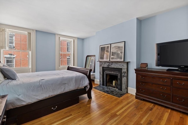 bedroom with light wood-type flooring and a premium fireplace
