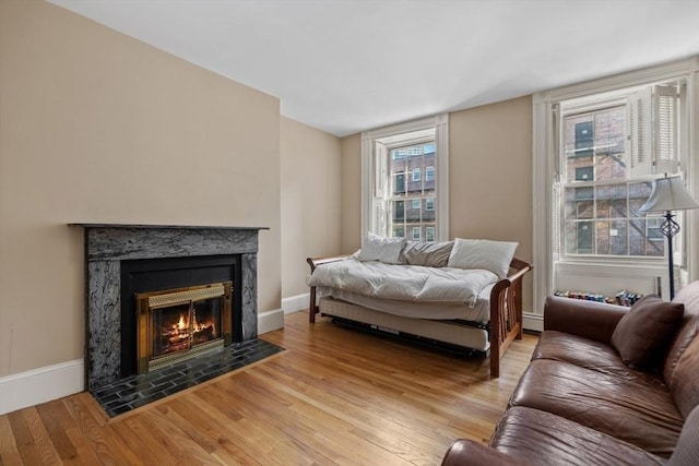 living room featuring a premium fireplace, light wood-type flooring, baseboards, and a baseboard radiator
