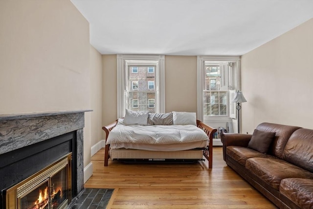 bedroom featuring multiple windows, baseboards, light wood-type flooring, and a fireplace