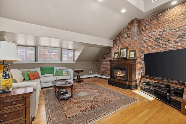 living room featuring lofted ceiling, a baseboard heating unit, light hardwood / wood-style floors, and brick wall