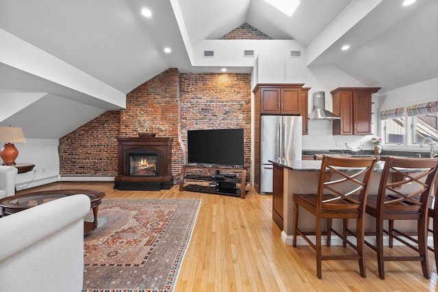living room with light wood-style flooring, vaulted ceiling with skylight, and visible vents