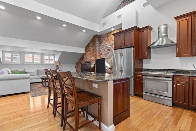 kitchen with wall chimney range hood, visible vents, vaulted ceiling, and appliances with stainless steel finishes