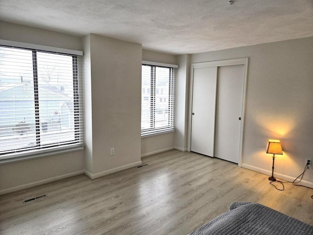 unfurnished bedroom featuring light hardwood / wood-style flooring, a textured ceiling, and a closet