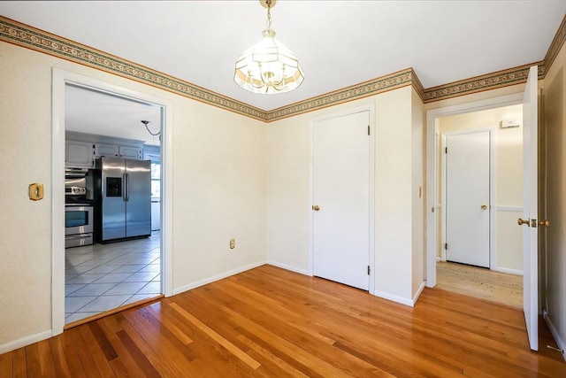 spare room with light wood-type flooring, baseboards, and ornamental molding