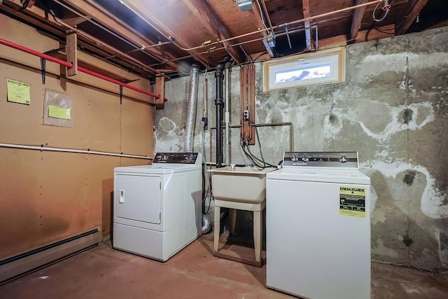 laundry area with a baseboard heating unit, laundry area, washing machine and dryer, and a sink