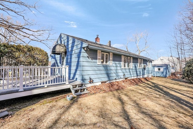 view of side of home featuring crawl space, a deck, and a chimney