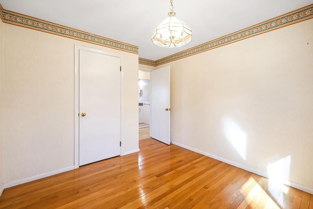 interior space featuring a notable chandelier, crown molding, light wood-type flooring, and baseboards