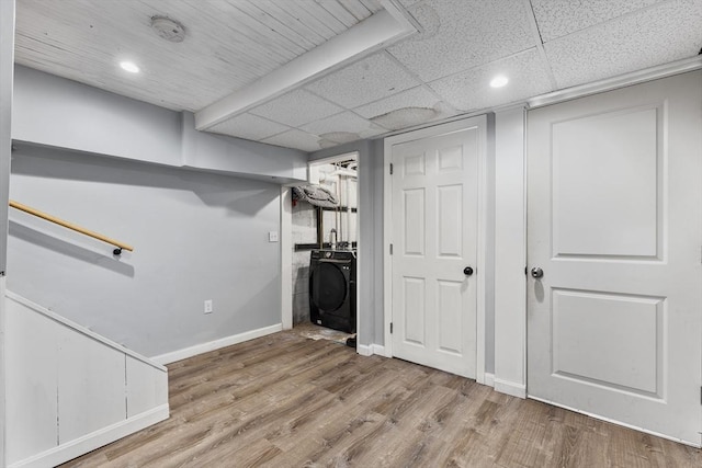 finished basement with washer and dryer, a paneled ceiling, baseboards, and wood finished floors