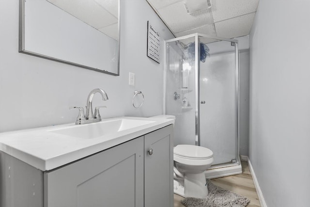 bathroom featuring vanity, a shower stall, toilet, and a paneled ceiling