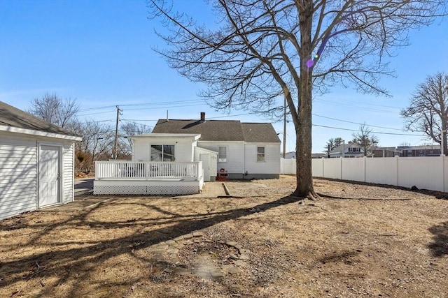 rear view of property with an outbuilding, a wooden deck, and fence