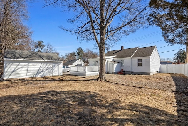 back of property with an outbuilding, a chimney, and fence